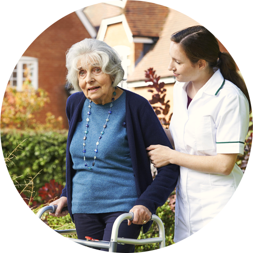 caregiver helping elderly woman to walk in the garden